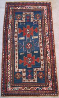  A Karachov Kazak Rug, dated 1911. There are some unusual design elements in this rug; two zoomorphic animals facing the same direction, double prayer arch, four dates and abstract motifs; note that the inner frame is totally different from the outer white ground stencil S border, one of the four dates is woven with ivory numbers against a brown ground box where as the other three are opposite, there is a small white framed box between the zoomorphic animal figures and a single standing hook motif (S) in the lower right side corner of the field. The rug is bold and yet atractive in its simplicity. Size: 6.5 x 3.5 ft (199x107 cm). Condition: Slightly oxidized browns, both ends refringed and completed by one inch, a small area in the blue gorund that has been repiled (aprox two inches by fifteen inches), even medium pile throughout, original selvedges and foundation, very good overall condition.