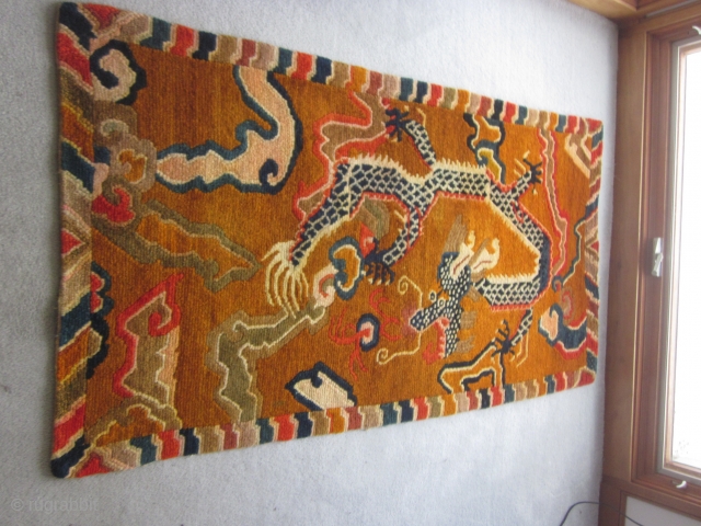 Tibetan khaden, mid-20thC,34 by 64 inches, dramatic tiger (What was the weaver smoking?)flying through an orange/brown sky filled with cloudbands and flaming pearlsd          
