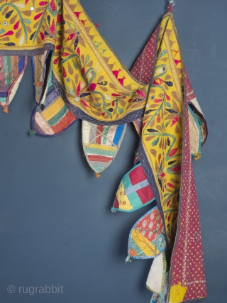 Rare and very large festival toran/tent banner, 450cm x 42cm (177 x 16.5 inches). Hand embroidered in vibrant pinks and greens on a beautiful Saffron ground. Gujurat, circa 1940.

The pennants, stitched together  ...