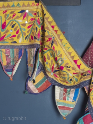 Rare and very large festival toran/tent banner, 450cm x 42cm (177 x 16.5 inches). Hand embroidered in vibrant pinks and greens on a beautiful Saffron ground. Gujurat, circa 1940.

The pennants, stitched together  ...