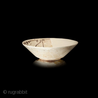 Fragment of a bowl, of conical form with steep flaring walls, stepped down to a low foot, slip-painted, decorated in brown on a slip ground with a single band of kufic script  ...