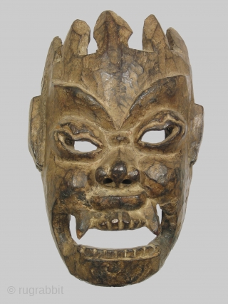 Nepalese or Tibetan mask depicting the diety Mahakala, 12 inches high of dense hardwood, 19th century or possibly earlier. The abstract treatment of the crown, which merges directly into the forehead, is  ...