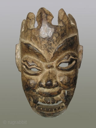 Nepalese or Tibetan mask depicting the diety Mahakala, 12 inches high of dense hardwood, 19th century or possibly earlier. The abstract treatment of the crown, which merges directly into the forehead, is  ...