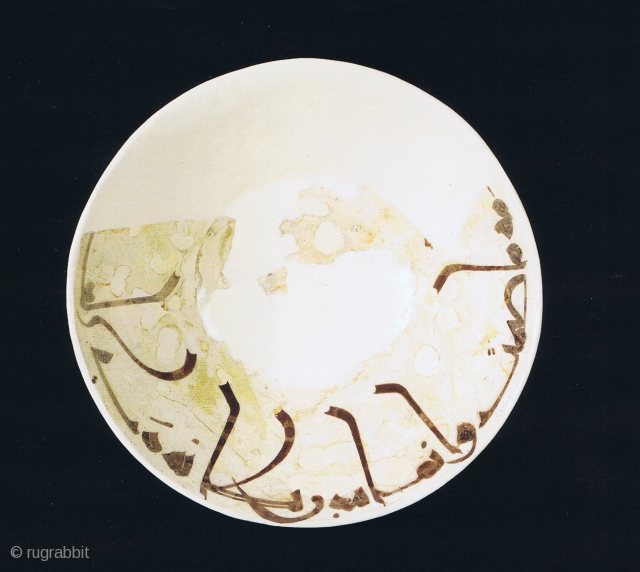 Fragment of a bowl, of conical form with steep flaring walls, stepped down to a low foot, slip-painted, decorated in brown on a slip ground with a single band of kufic script  ...
