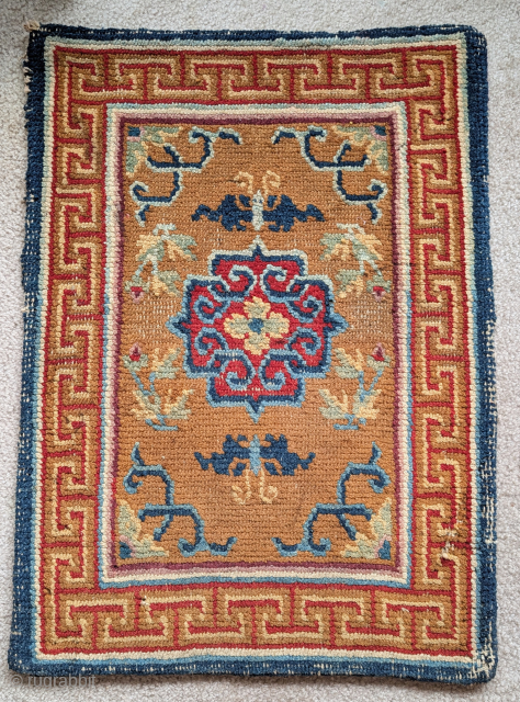 Tibetan small rug or saddle top with a camel ground, abrashed blue vine-scroll and a red central quatrefoil medallion. Nice auspicious bat-like butterflies          