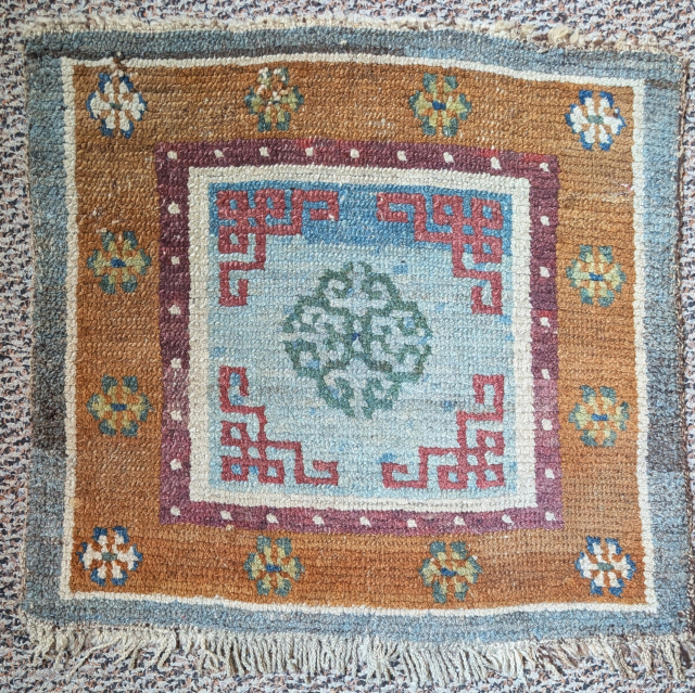 Antique Tibetan khagangma seating square. Elegantly drawn central sea-green colored quatrefoil medallion floating against a sky-blue abrashed field. Unusual but successful color palette using all natural dyes including double-dyed plum colored corner-pieces  ...