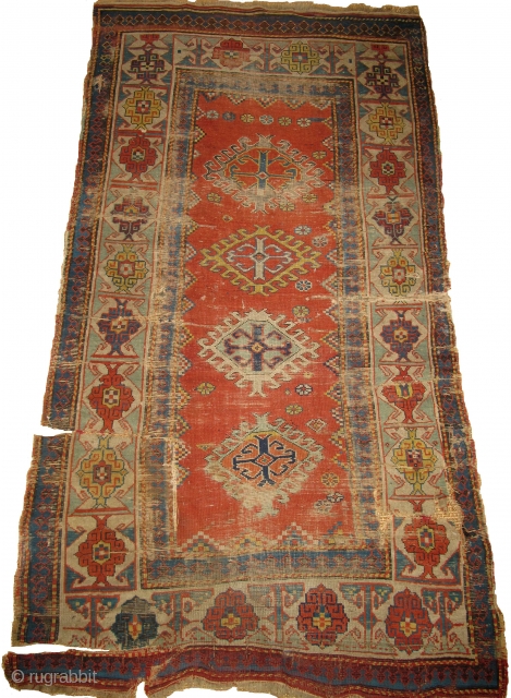 Kazak Rug, Old, Colorful with a Kufic border. Several blues and greens, two natural oranges, great aubergine highlights. In "as found" condition. browns are corroded and there are several rips or rather  ...