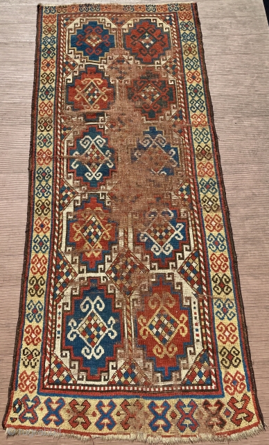 A 19th C. Memling-gul Kazak long rug. 41” x 97” (104 cm x 246 cm) Interesting yellow-ground border with archaic double rams-horn design.  Substantial areas without pile in the center, but  ...