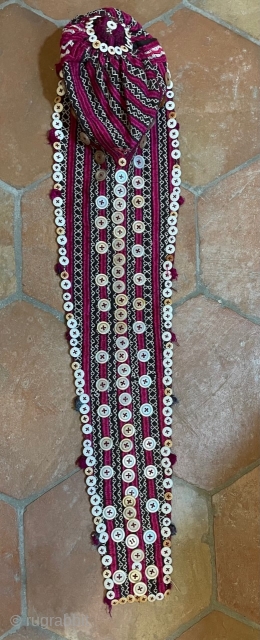 Tajik young girl's cap with the traditional "tail" to hide the plait. The cap is heavily embroidered in stripes of cherry red, alternating with white geometric bands, which show the dark ground.  ...