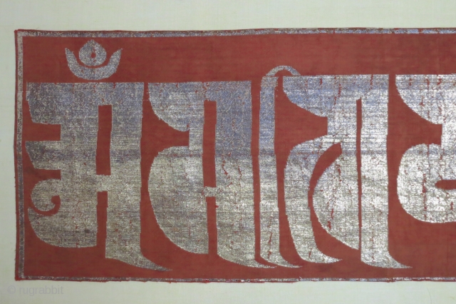 Chinese silk panel displaying the text "0m mani padme hum" (the jewel is in the lotus) in a Tibetan script with gold leaf/foil attached to a substrate of paper strips and made  ...