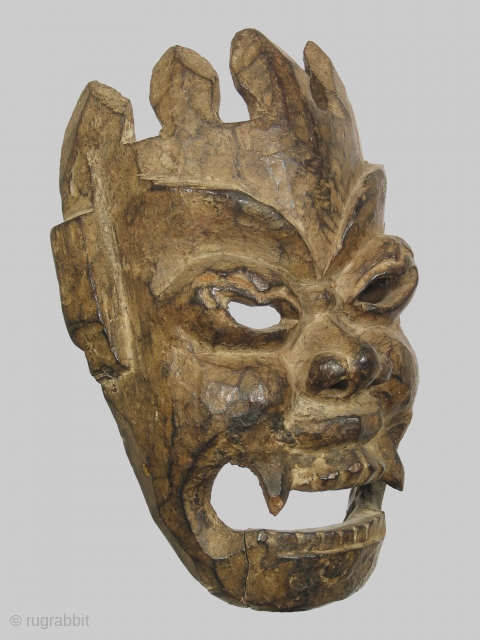 Mask depicting the deity Mahakala, wood, Nepal or Tibet, 12 inches high, 19th c., or possibly earlier. The abstract treatment of the crown, which merges directly into the forehead, is interesting and  ...