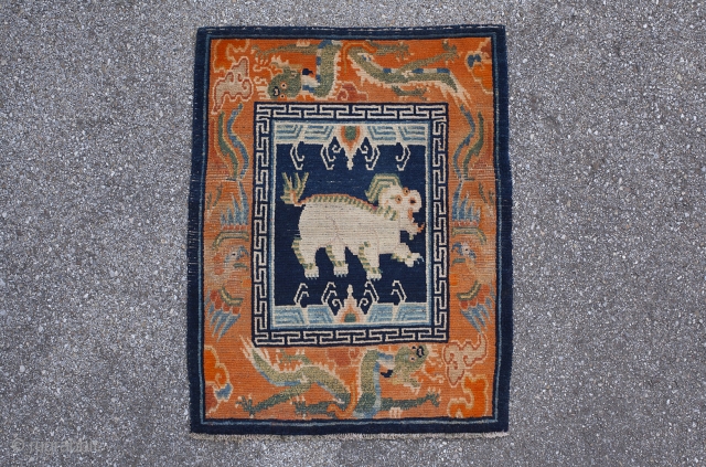 Charming Tibetan sitting rug depicting a snow lion. Dragon border. Lovely animals with great features. Typical signs of wear for a saddle top rug. Circa 1920. 70*57cm.      