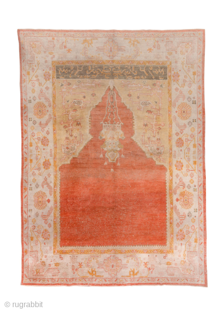 This antique Oushak rug showcases the beauty of Anatolian weaving with its striking open field in warm terracotta red, framed by soft blush, ivory, and golden tones. The spacious design and gentle  ...
