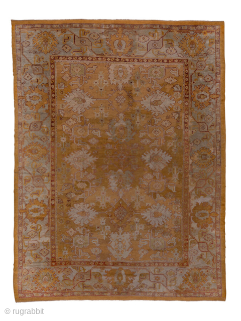 This antique Oushak rug, woven circa 1920 in Western Anatolia, showcases a glowing golden field complemented by soft gray and muted red accents. The spacious design features stylized floral medallions and geometric  ...
