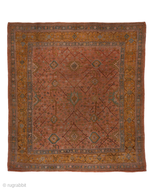 This antique Turkish Oushak rug, woven circa 1900, showcases a beautifully understated lattice and medallion design on a rich rust field framed by a wide gold border with delicate floral detailing. The  ...