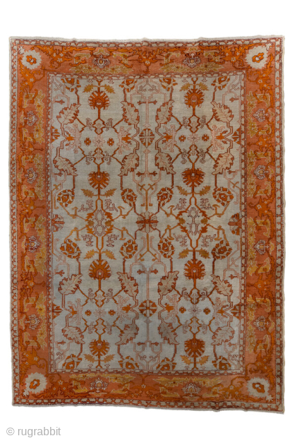 This antique Oushak rug, woven circa 1900 in Western Anatolia, showcases the region’s signature large-scale, open design with striking color contrasts. The ivory ground is adorned with an allover floral lattice rendered  ...