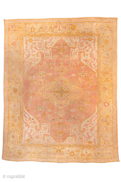 This antique Oushak rug, woven around 1900, displays the elegance and warmth for which Anatolian weavings are celebrated. The spacious field is rendered in a rare blush-rose tone, subtly shifting across the  ...