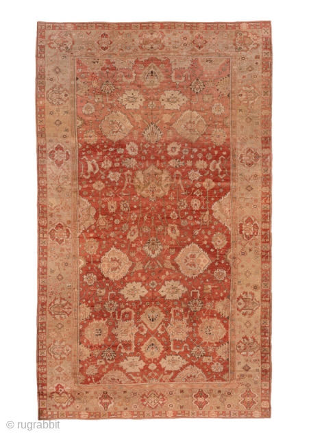 This impressive antique Oushak rug showcases a richly detailed allover palmette and vine pattern set against a warm terracotta field. The palette features soft tones of beige, sand, and muted coral, beautifully  ...