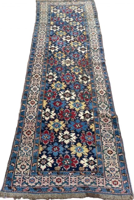 A Splendid blue ground star and rosette Caucaian Kuba runner, wonderful colours, well drawn field and green kufic border, original macrame ends, minor moth damage otherwise full pile, all original no repairs,  ...