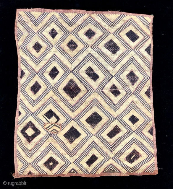 Kuba raffia cut pile man's status cloth.  Probably Bushong people. This example has a large scale graphic with "primitive" feel with its characteristically loosely tufted cut pile.  The colors are  ...