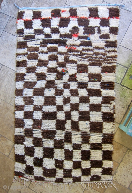 Azilal rug, middle Atlas mountain region of Morocco. Undyed cream and brown wool in a checker pattern on a cotton weft, with colorful boucherouite details of recycled cloth. Ca. 1980-1990. Has served  ...