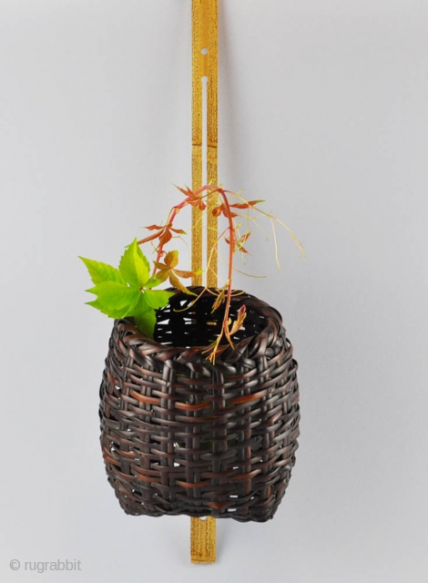 Japanese flower wall basket (hanakago) with a suspension loop on the back.  Plating of dark bamboo strips.  Signed Kōchikusai (?) . These hanging baskets are generally hung on the wall or on the  ...