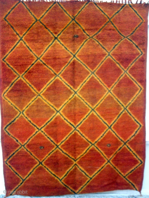 MOROCCAN RUG. This very old piece is from Rehamna which lies in the Haouz district, west of Marrakech. It has woollen warps and wefts and the mellow madder field has lattice designs  ...