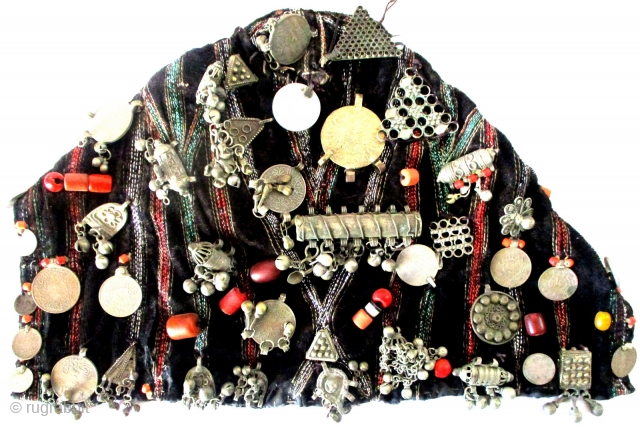 YEMENI WOMAN'S EMBELLISHED HAT upon which a multitude of coins, charms, beads of amber and coral, amulets and other superstitious and unusual items are displayed. Most rare is the use of an  ...