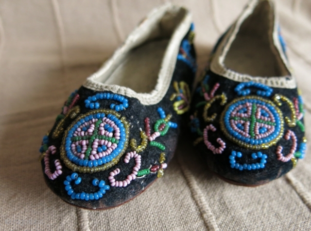 A pair of glass beaded children's shoes on velvet.                        