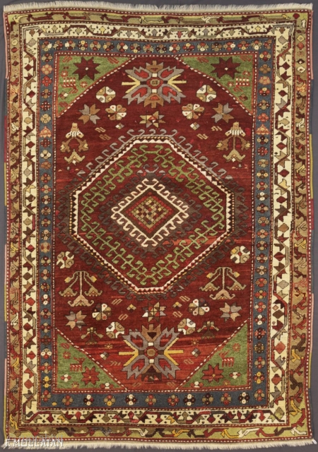 A fine Kazak rug, South Caucasus.

The abrashed deep rust field with various angular floral motifs and hooked panels around double hooked octagon medallions containing hooked bars, Green stellar flower head and animal  ...