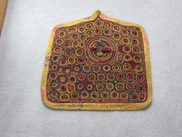 Tibetan: Village-improvised for the local temple. An embroidered throne back chair textile in Gelupga colors and surrounded by yellow ground Chinese silk fragments. In the upper middle of the piece is an  ...