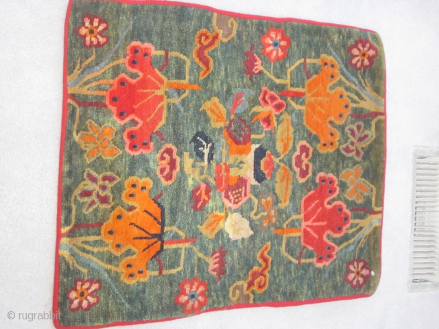 Tibetan mat,23 by30 inches, extravagant floral and cloud band display on abrashed green ground, c.1930                  