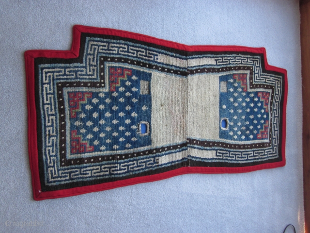 Tibetan notched saddle bottom, 24 by 51 inches; soft,floppy weave; classic design with frogs foot design on blue ground,red fretwork, and pearl border; repiling in one area in upper blue field (not  ...