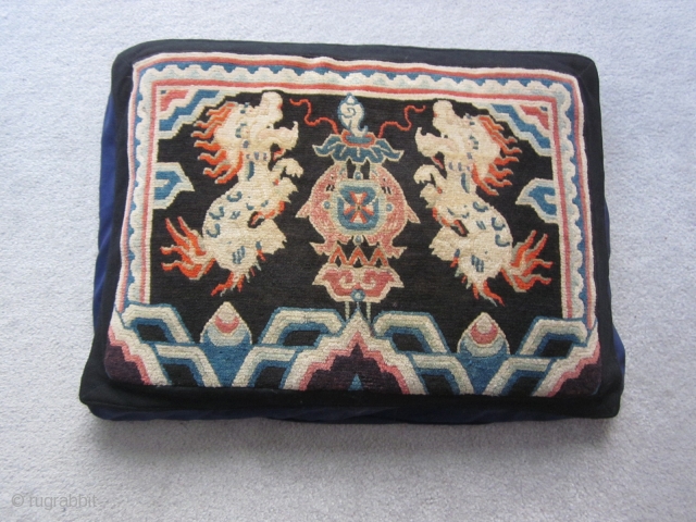 Tibetan : Made up pillow with rug face, 1'7" by 2'3", snow lions facing fish and the conch shell. Looming up from below are two large flaming pearls. c.1930    