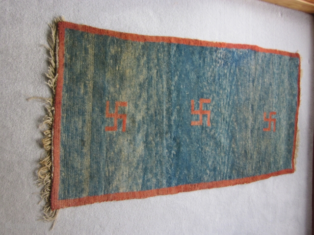 Tibetan khaden, 29 by 55 inches, three red swastikas on abrashed blue ground, natural dyes, pre-1900.                 