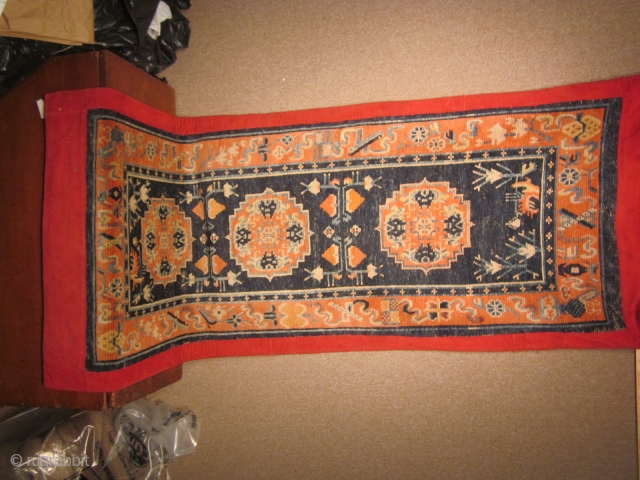 Tibetan: Long runner, 35 by 88 inches, three "coin" design, with floral elements. C 1930, red corduroy surround.               