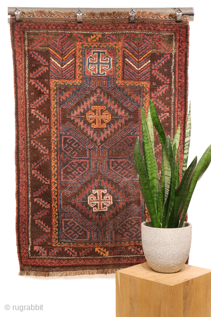 An antique Baluch prayer rug from Afghanistan, featuring an elegant, dark palette of natural dyes, including a deep indigo blue. The field contains two medallions, whose distinctive cross-shaped interior motif is echoed ...