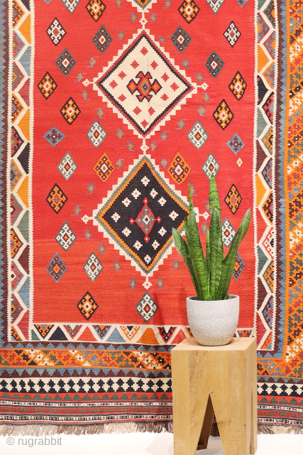 This antique Qashqai kilim is a striking example of tribal weaving, created with rich, naturally dyed colors that have retained their depth and vibrancy over time.

The main field features a bold deep-red  ...