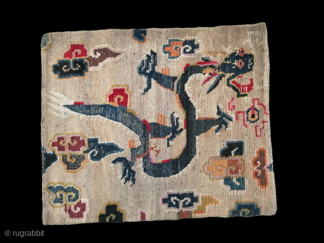 A white groung Tibetan Dragon mat. The Dragon chasing a flaming pearl and surrounded by clouds. 19th century.               