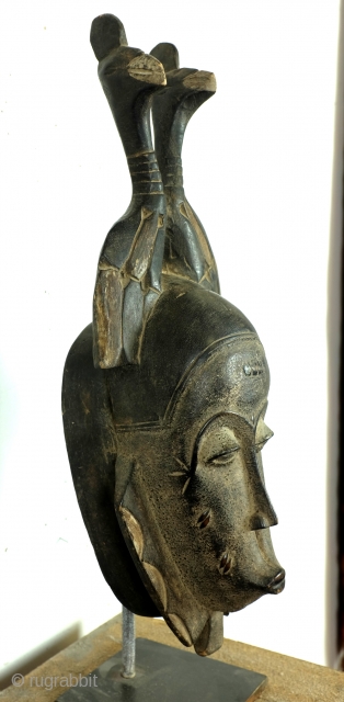 Baoulé, 
The BAOULE masks are known in African art for the smoothness of their features, protruding mouth, half closed eyes. 
The mask is topped with a headdress decorated with towering braids. 
The  ...