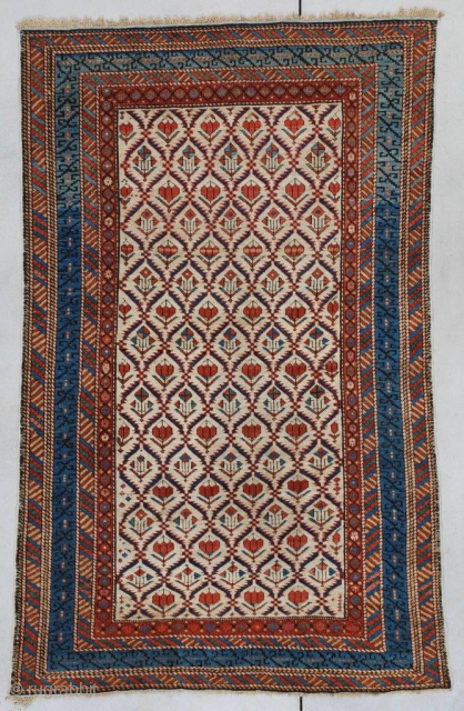 This first-half 19th-century Kuba/ Shirvan #7347 measures 4’0” X 6’4” (121 x 195 cm). It has an ivory field divided into segmented diamonds set off by serrated blue edges each containing a  ...