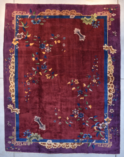 This circa 1925 Art Deco Chinese #8187 handmade wool Oriental Rug measures 9’0” X 11’8”. The field is a deep ruby red with a geometric and floral motif. There are flowers growing  ...