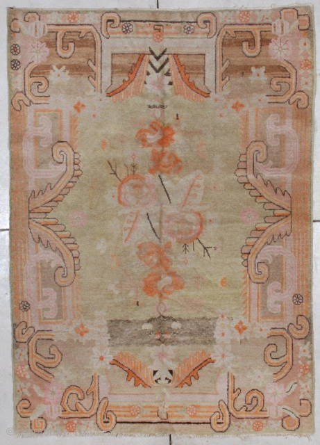 This circa 1920 Khotan carpet #7064 measures 4’8” x 6’7”.  It has a pale lime green field with orange, pink and brown flowers in the center. It is a  handwoven  ...