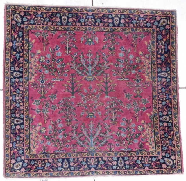 This circa 1920 Sarouk measures 4’0” X 4’0”. It has a dusty rose field with a one way floral design of trees and flowering branches all encompassed with a border of cypress  ...