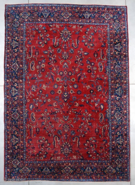 A circa 1900 antique Kerman measures 10’ x 14’ (305 x 427 cm). It has a red field with an overall floral motif in several shades of blue and ivory with some  ...