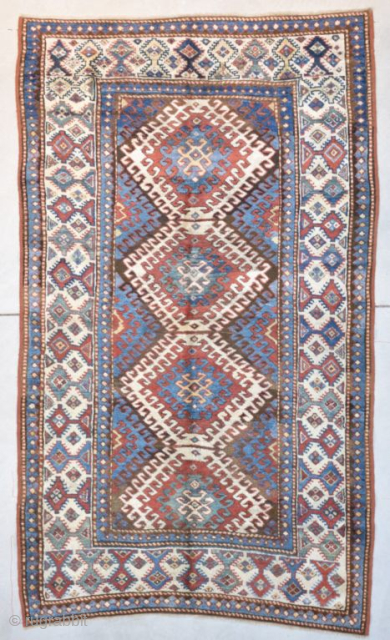 This third quarter 19th century Kazak measures 4’1” X 6’9”. It has 3 ½ diamond shaped medallions running up the field surrounded with latchhook borders in ivory. The center motif flows inward  ...