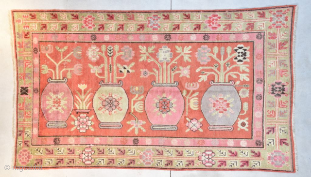 This circa 1920 Khotan handmade wool Oriental rug measures 8’1” X 5’0”. It has a depiction of four urns. Two urns are in pink, one in very pale green and one in  ...