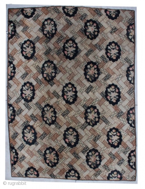 This mid-19th-century American hooked rug measures 8’9” x 11’11”. The background design is of different colored bricks displayed in the basket weave design.  There are diagonal rows of black scalloped ovals  ...