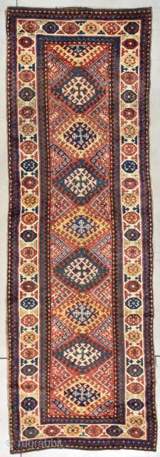 This third quarter 19th century antique Kazak-Gengi runner #8088 measures 3’1” X 10’9”. It has a tomato red ground with 8 ½ hooked medallions going up the center in yellow, green, mustard, ...