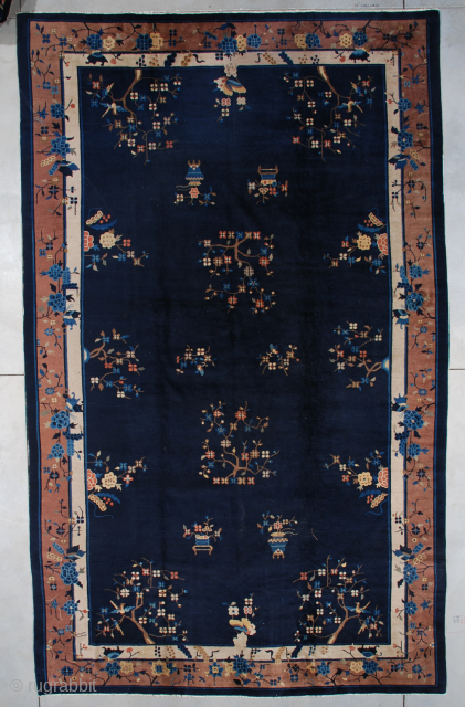 This circa 1900 Peking Chinese Oriental rug measures 8’10” x 14’6” (273 x 444cm). It has a navy blue field with flower sprays in brown, rust, ivory and light blue spread through  ...